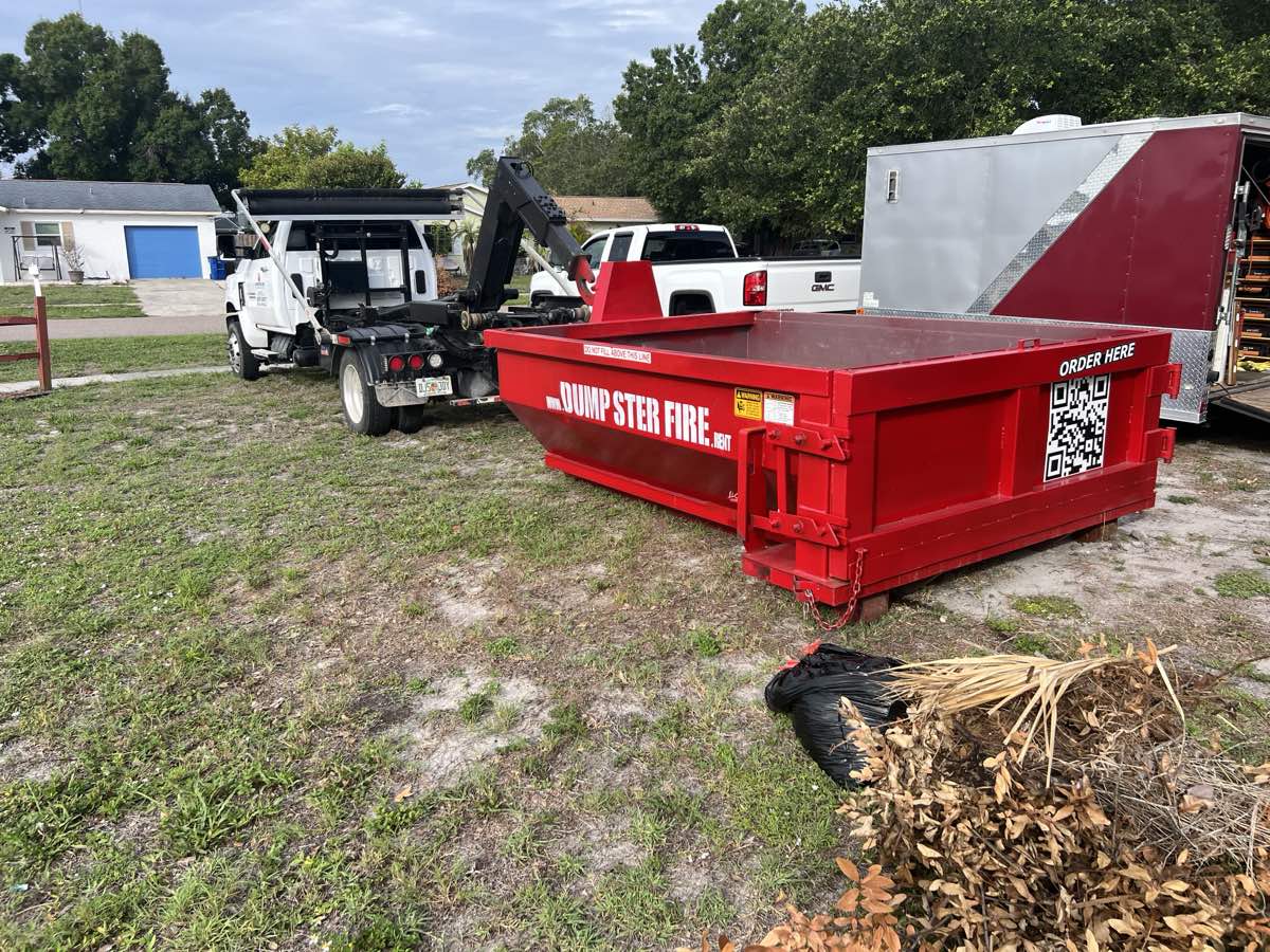 A red 7-yard Dumpster Fire roll-off dumpster and hook-lift truck on a Southwest Florida job