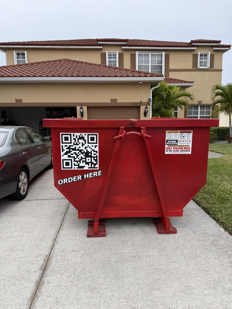 A red Dumpster Fire roll-off dumpster in a coastal Southwest Florida driveway