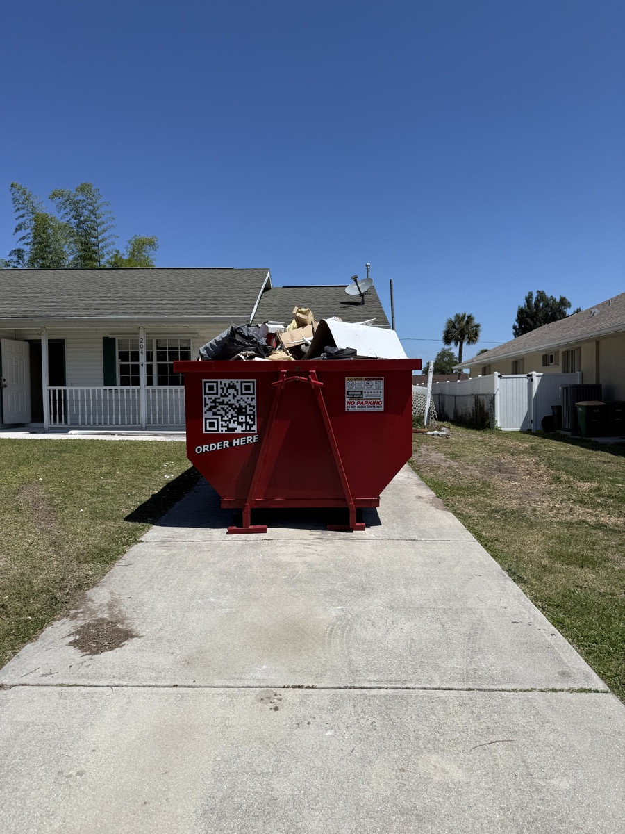 A red Dumpster Fire roll-off dumpster in a Southwest Florida driveway