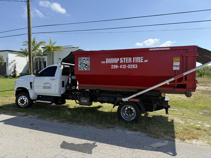 The Dumpster Fire truck and red roll-off dumpster on a job in Southwest Florida