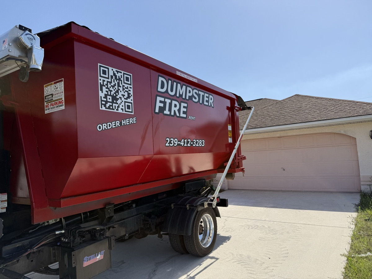 A red Dumpster Fire roll-off dumpster in a Southwest Florida driveway