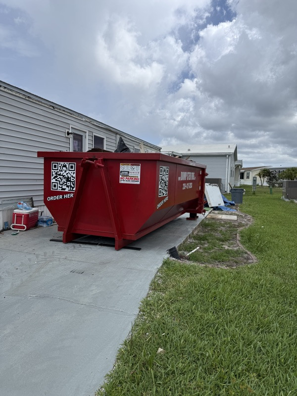 A red Dumpster Fire roll-off dumpster fit beside a Florida home
