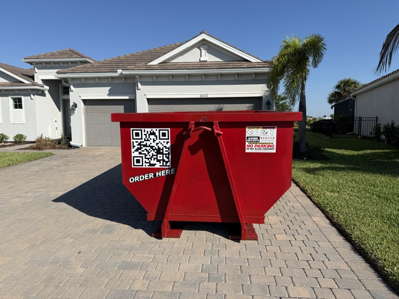 A red Dumpster Fire roll-off dumpster in a driveway in Southwest Florida