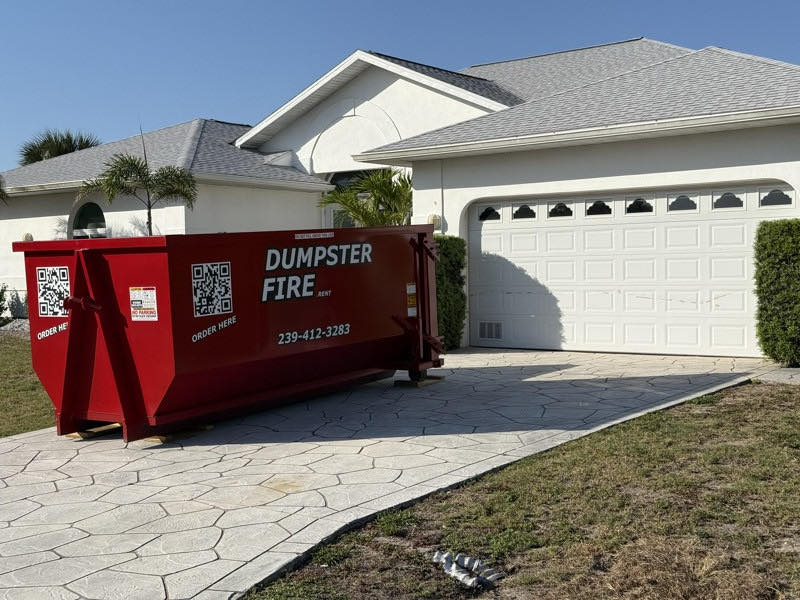 A red Dumpster Fire roll-off dumpster in a Port Charlotte driveway during a move-out
