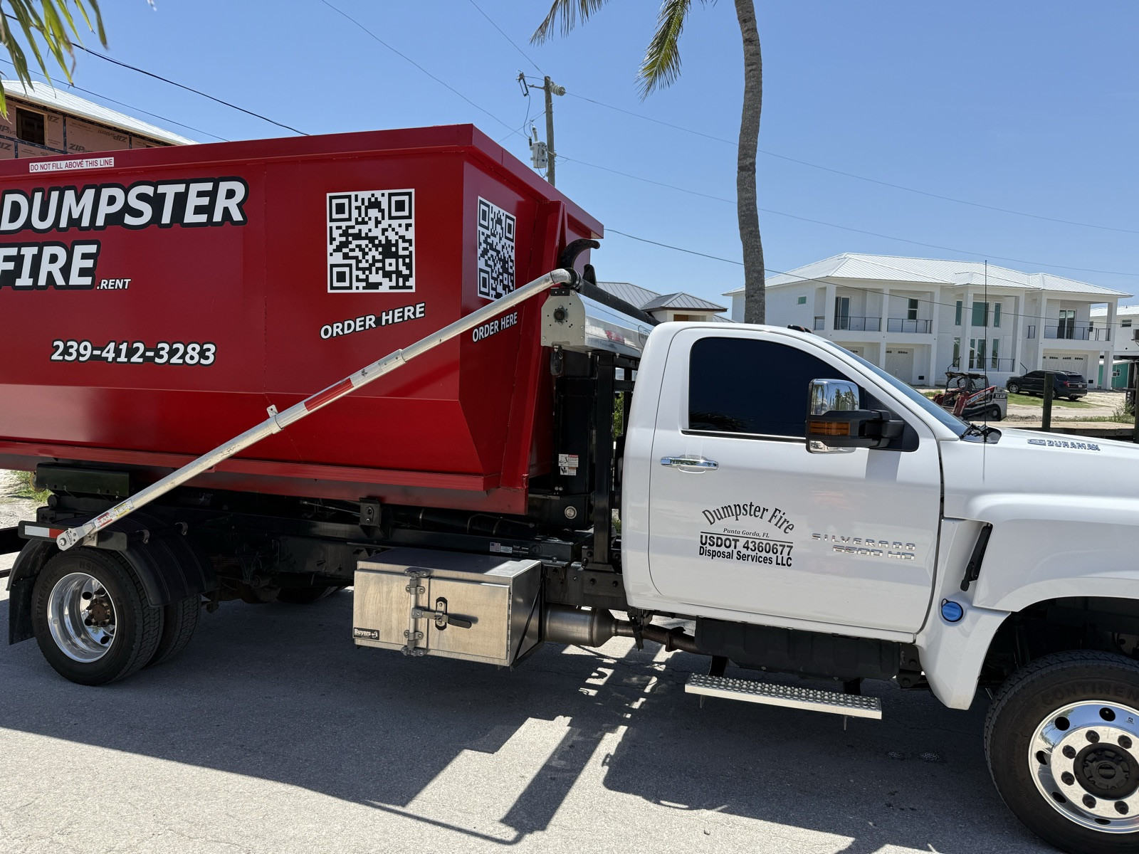 The Dumpster Fire truck and a red roll-off dumpster in Port Charlotte, FL